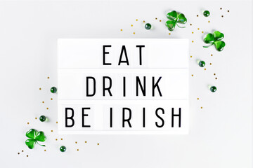 Lightbox with Saint Patricks day greeting text, shamrock symbols made of green hearts and stars confetti on white background. Flat lay Irish holiday party card Spring 17 march lucky clover design