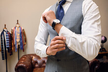 Man In Gray Waistcoat Fastening Shirt Cuff In Tailors Boutique
