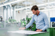 © Daniel Ingold/Westend61 - Businessman looking at floor plan while working in industry