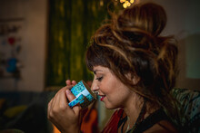 Close-up Of Hippie Woman Drinking Coffee While Sitting In Living Room