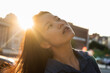 © NOVELLIMAGE/Westend61 - Close-up of beautiful woman looking up against bright sunset sky during weekend