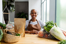 Woman With Apron In Kitchen , Unpacking Freshly Bought Organic Fruit And Vegetables