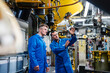 © Daniel Ingold/Westend61 - Male professionals discussing while examining manufacturing equipment in industry