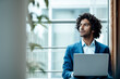 © Joseffson/Westend61 - Thoughtful male professional looking away while sitting with laptop against window at workplace