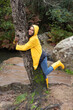 © Sebastian Kanzler/Westend61 - Happy female hiker wearing yellow raincoat embracing tree in forest