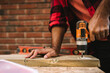 © Maskot - Midsection of man using drill machine on plank while renovating during summer