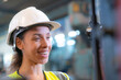 Portrait of woman worker beautiful face with eye confident and wearing working suite dress and safety helmet at heavy machine in industry factory. Brazilian worker concentrate on workplace.