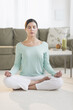 © Tetra Images/Tetra Images - Woman meditating in living room