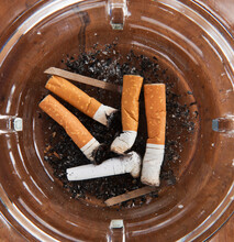 Close Up Of Cigarette Butts In Glass Ashtray