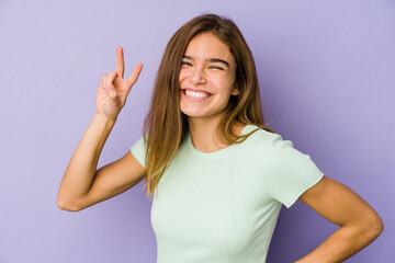 Young skinny caucasian girl teenager on purple background showing number two with fingers.