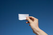 © Winslow Productions/Tetra Images - Hand of woman holding paper note against blue sky