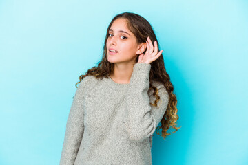 Wall Mural - Young caucasian curly hair woman isolated trying to listening a gossip.