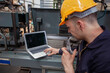 © nikomsolftwaer - Factory worker in a hard hat is using a laptop in a factory. working