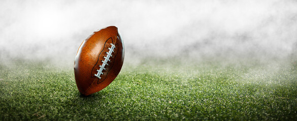 Wall Mural - American football ball on the grass of a stadium