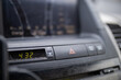 © Christian - Emergency blinkers button and digital clock on dusty car dashboard