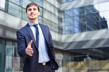 Smiling businessman standing outdoors near the modern buildings .