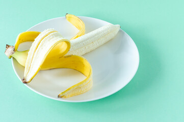 Wall Mural - Ripe tasty banans on a plate on blue background. Healty eating concept