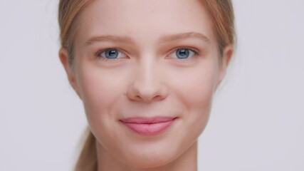 extreme close-up beauty portrait of young light-haired woman who softly touches her face skin with h