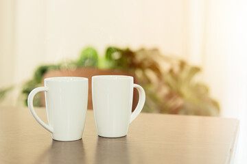 Coffee in the morning, two white tea cup mug placed on wooden table at home.