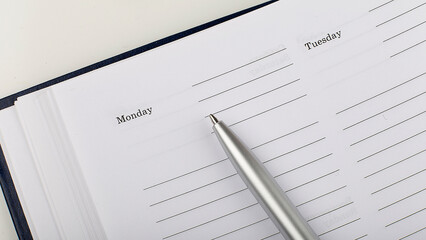 Poster - silver pen on open business agenda on white background
