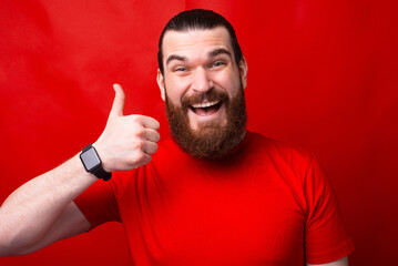 Wall Mural - A joyful young man is holding a thumb up smiling and looking at the camera .