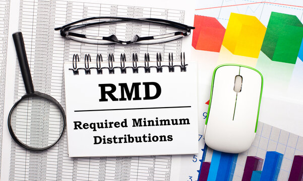 The desktop has a magnifying glass, a computer mouse, color graphics, glasses and a blank notepad with the text RMD. Business concept