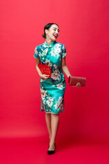 Smiling Asian woman wearing oriental qipao dress holding Ang Pao or red envelopes and wallet in hands on studio background for Chinese new year spending concepts, text means great luck great profit