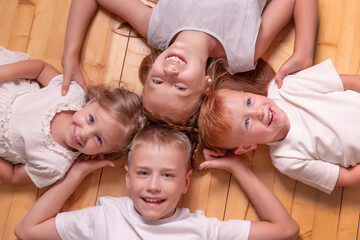 brothers and sisters. 4 children. girls and boys lying on the floor, looking at camera.