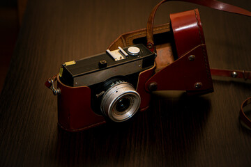 old camera on a wooden table, photographic equipment, retro camera on a brown background, vintage camera, leather case, brown antique