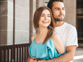 Wall Mural - Portrait of smiling beautiful female and her handsome boyfriend. Woman in casual summer jeans dress. Happy cheerful family. Female having fun. Couple posing on the street background