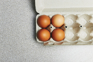 Wall Mural - Culinary class in a kitchen. Four tinted brown chicken eggs in an open carton box on the table ready for cooking.