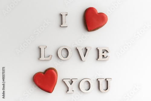 Inscription I LOVE YOU and red heart shaped gingerbread, white background. Valentines day