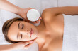 © LIGHTFIELD STUDIOS - Top view of beautician holding container with face mask near woman on massage table