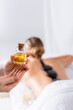 © LIGHTFIELD STUDIOS - cropped view of masseur holding bottle with oil near client