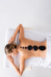 © LIGHTFIELD STUDIOS - top view of young pleased woman getting hot stone massage