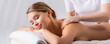 masseur massaging pleased client lying on massage table, banner