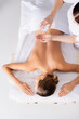 © LIGHTFIELD STUDIOS - top view masseur holding glass bottle and pouring massage oil on hand near client