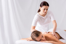 Brunette Masseur Massaging Back Of Woman On Massage Table In Spa Salon