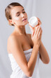 © LIGHTFIELD STUDIOS - young woman with closed eyes and cream on face holding jar on white
