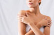 © LIGHTFIELD STUDIOS - cropped view of young woman touching bare shoulders on white