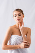 © LIGHTFIELD STUDIOS - young woman with closed eyes wrapped in towel touching face on white