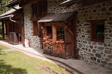 Wall Mural - A stone house in the mountains with stacked wood logs (Trentino, Italy, Europe)