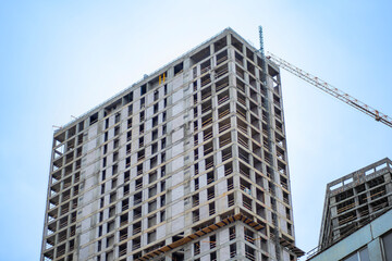 Wall Mural - Residential high-rise building under construction. Unfinished house on a construction site with cranes.