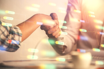 Double exposure of data theme hologram and handshake of two men. Partnership in IT industry concept.