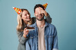 Young happy girl with birthday cake covering eyes of excited guy