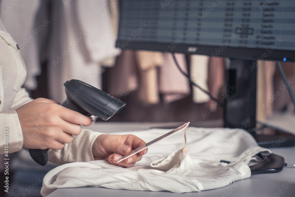 A warehouse woman employee accepts clothes using barcode scanner ...