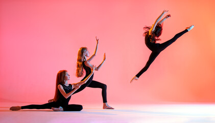 Wall Mural - group of three ballet girls with long flowing hair in black tight-fitting suits dance on red background