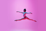 Fototapeta Londyn - Flying, jumping. Young and graceful ballet dancer on pink studio background in neon light. Art, motion, action, flexibility, inspiration concept. Flexible caucasian ballet dancer, moves in glow.