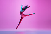 Flying, Freedom. Young And Graceful Ballet Dancer On Pink Studio Background In Neon Light. Art, Motion, Action, Flexibility, Inspiration Concept. Flexible Caucasian Ballet Dancer, Moves In Glow.