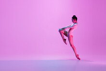 Urban Style. Young And Graceful Ballet Dancer On Pink Studio Background In Neon Light. Art, Motion, Action, Flexibility, Inspiration Concept. Flexible Caucasian Ballet Dancer, Moves In Glow.